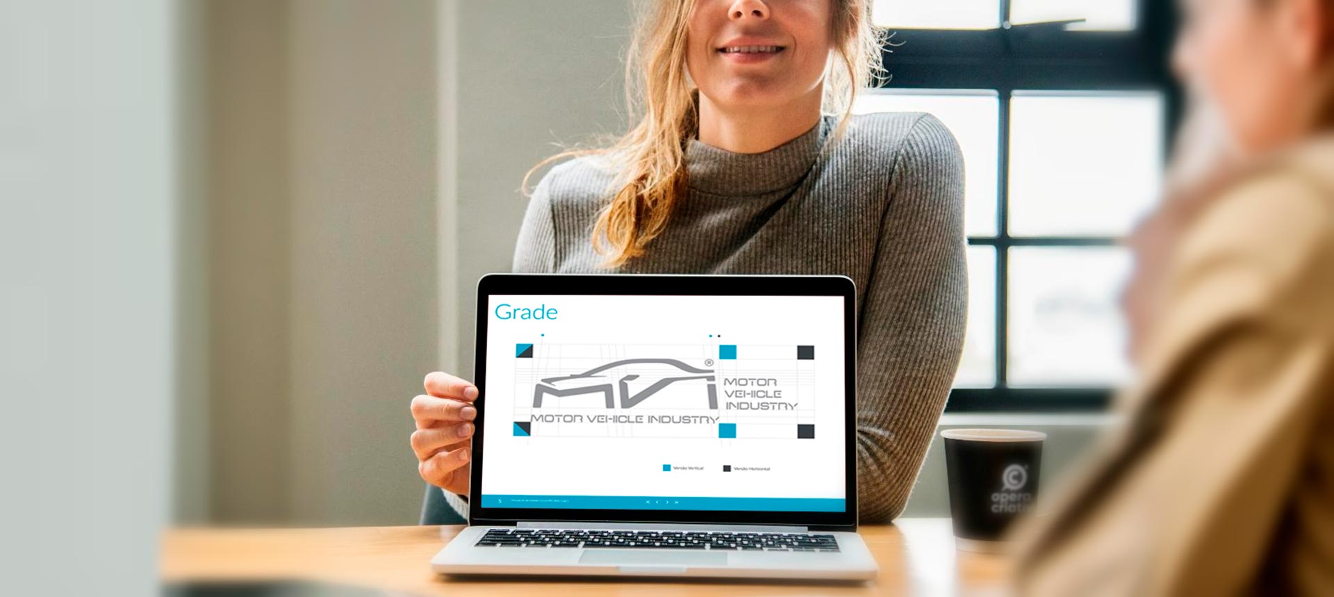 Apresentação em tela de laptop da grade de construção (Grid) do logotipo MVI criado pela Ópera Criativa para a Atlas Copco Brasil. Para ilustrar o Artigo sobre Manuais de Identidade Visual da Banca da Ópera.